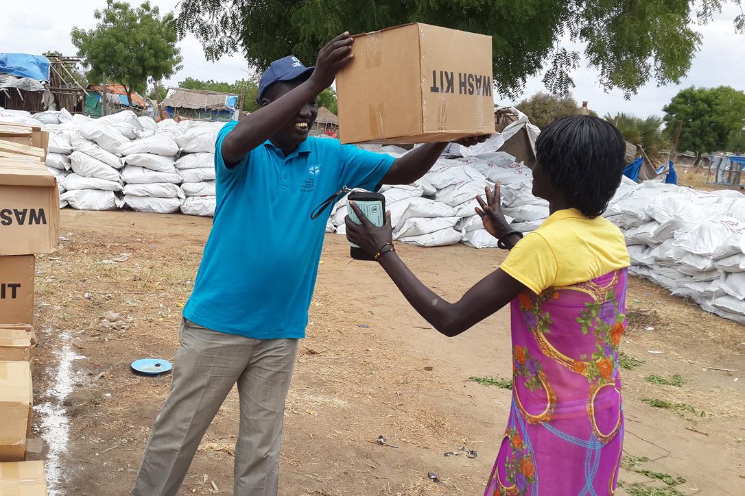 LWF staff provides a displaced woman in Bor with a water, sanitation and health kit. Photo: LWF/South Sudan