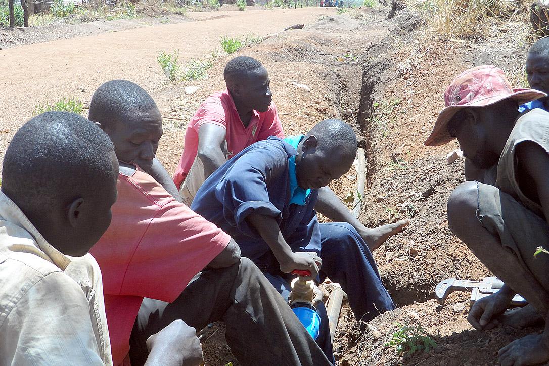 LWF water technicians fix a pipe in Ayilo2 refugee camp, Adjumani district, Uganda. Photo: LWF Uganda