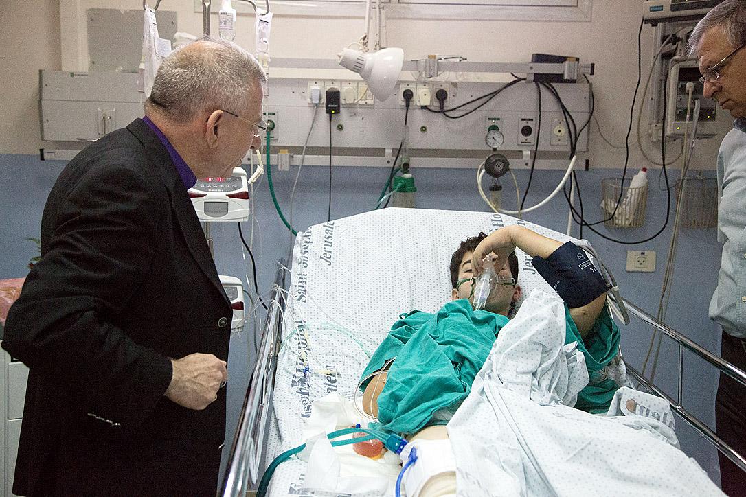 Bischof Munib Younan spricht mit einem verletzten Jungen auf der Intensivstation des St. Joseph‘s-Krankenhaus. Foto: D. Hudson/ELKJHL