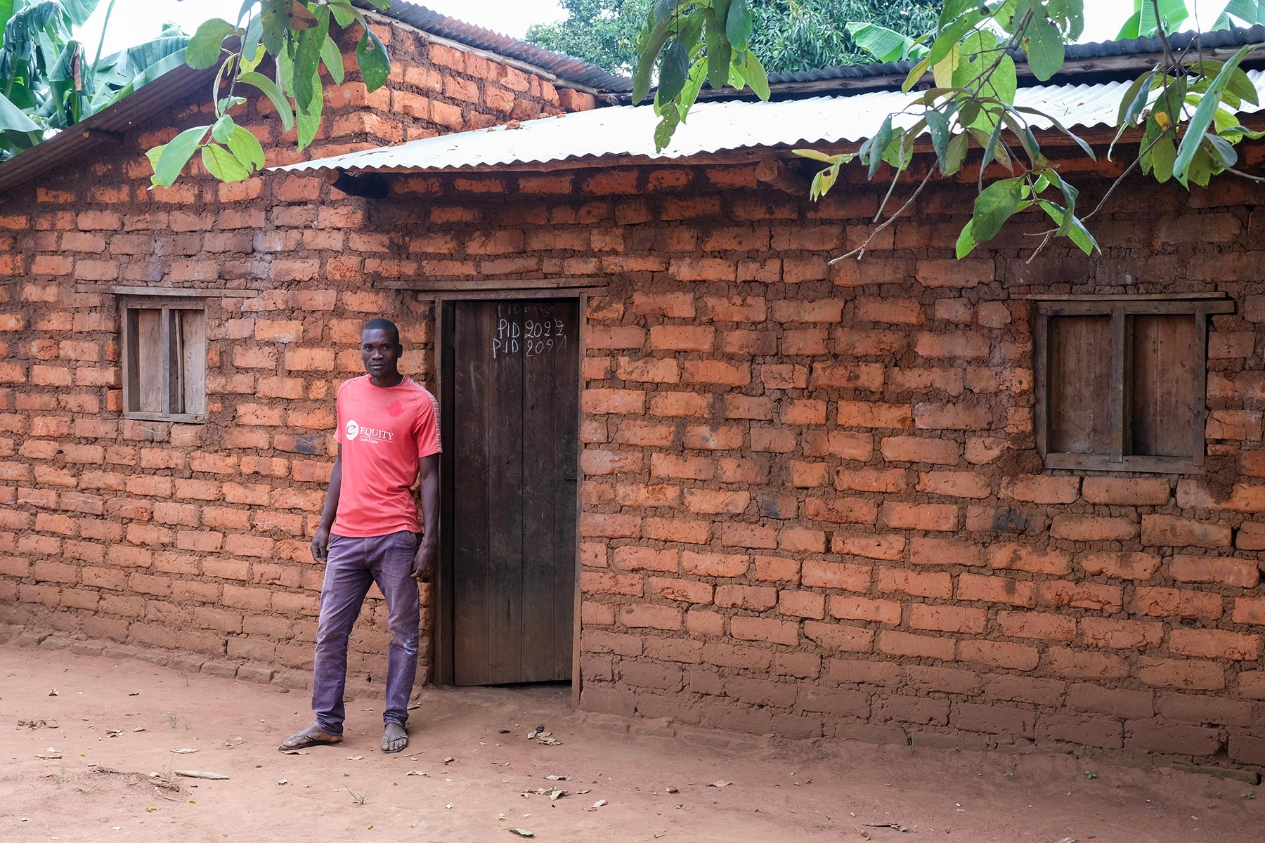 Jonas Hakizimana, a member of the cooperative, in front of his house with a new tin roof.