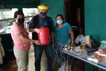 Hans-Jürgen Johnke (middle), Mission EineWelt staff working in El Salvador, hands over food and a canister for washing hands to members of the congregation in El Volcan. Photo: MEW 