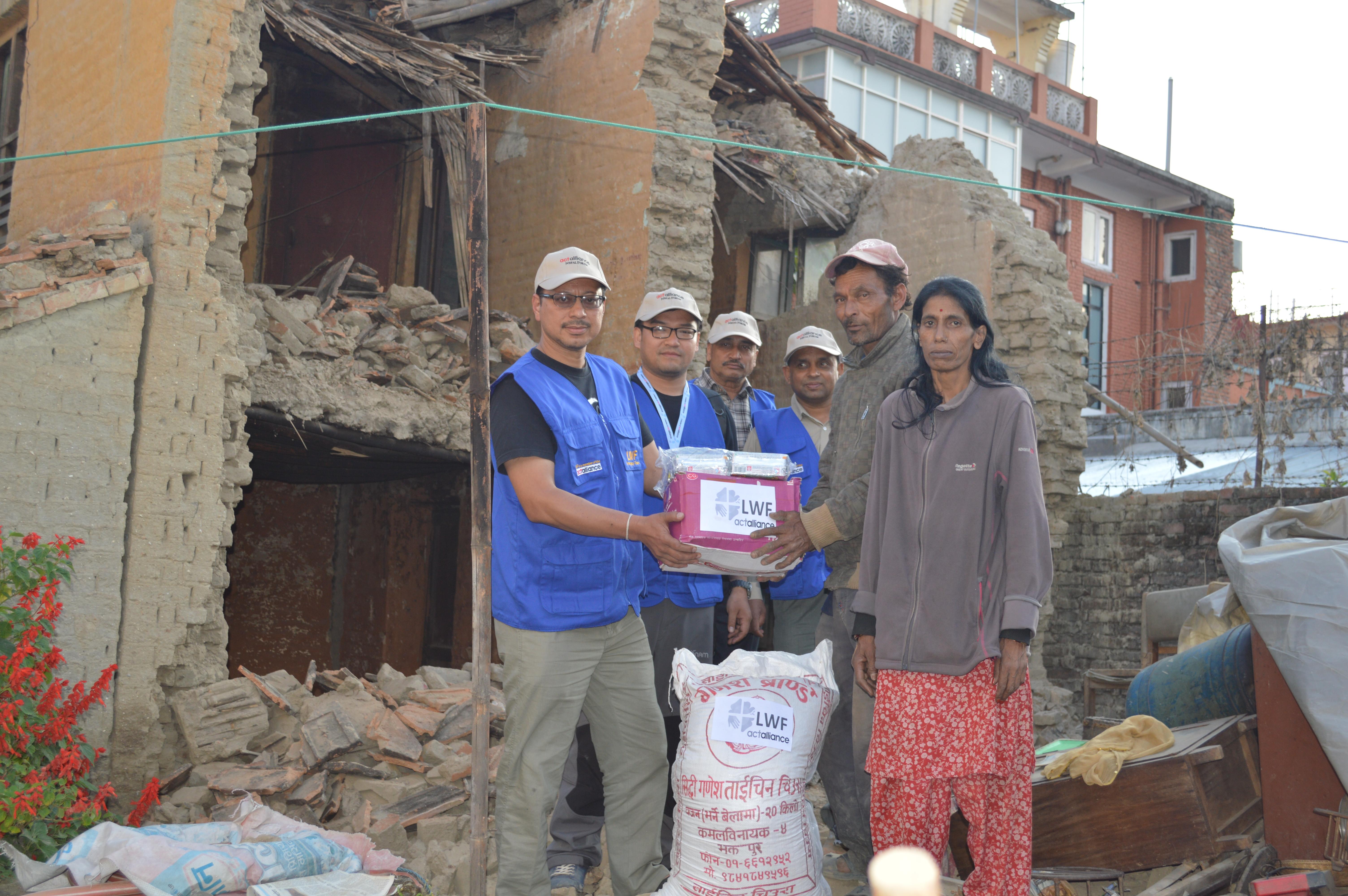 Der LWB übergibt Nothilfe-Material (hier: Fertignahrung) an eine Familie, deren Haus zerstört wurde. Bildnachweis: LWB Nepal