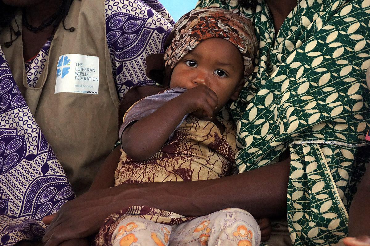 A child is cradled by her mother during one of the meetings of the peace committee in Borgop camp, Cameroon. The committee mediates conflicts involving the refugees, and has also managed to reduce domestic violence and violence against children. Photo: LWF/ C. KÃ¤stner