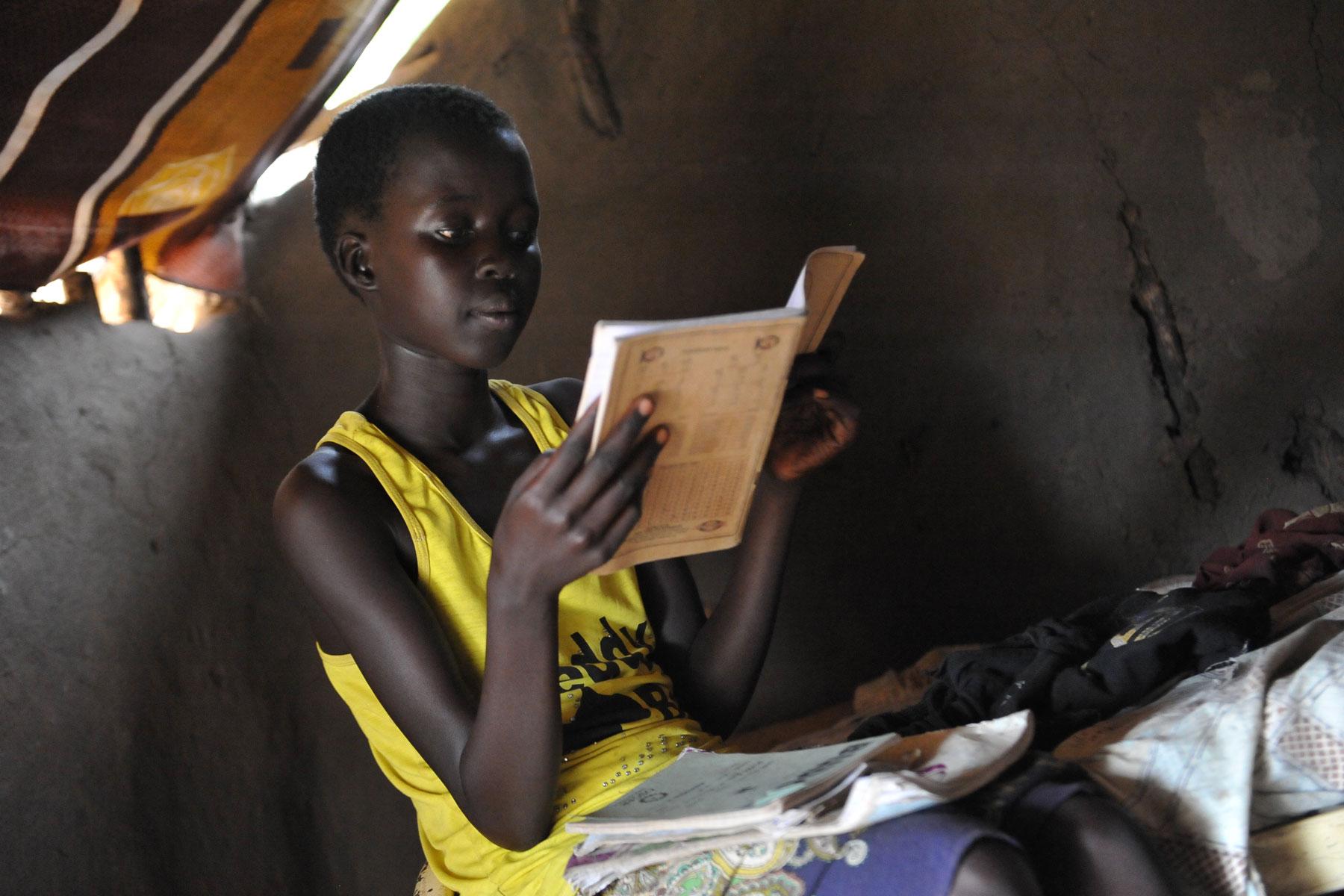 Ein junges Flüchtlingsmädchen aus dem Südsudan macht in Adjumani, Norduganda, ihre Schularbeiten. Die verbesserte Einschulungsrate von Mädchen wird bedroht durch die fehlende Versorgung mit Hygieneartikeln. Foto: LWB/M. Renaux