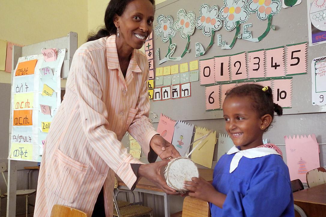 Teacher Almaz Tesfaldet shows five-year-old Luz how to play a traditional drum at the Lutheran church-run pre-school in Asmara. The Eritrean Lutheran church kindergartens in the capital and three remote villages provide learning and recreation space for children from many faith backgrounds. Photo: LWF/Rainer Lang