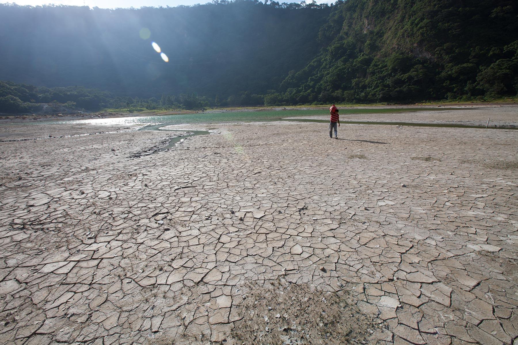 At the lagoon of AlegrÃ­a, UsulutÃ¡n, El Salvador, water levels have dropped dramatically in the drought that is affecting the region. Here, where the water has receded hundreds of meters, a man carries a âcantaroâ of water across the dry lagoon bed. The effect of climate changes in the Central American region are already extreme. Photo: LWF/Sean Hawkey