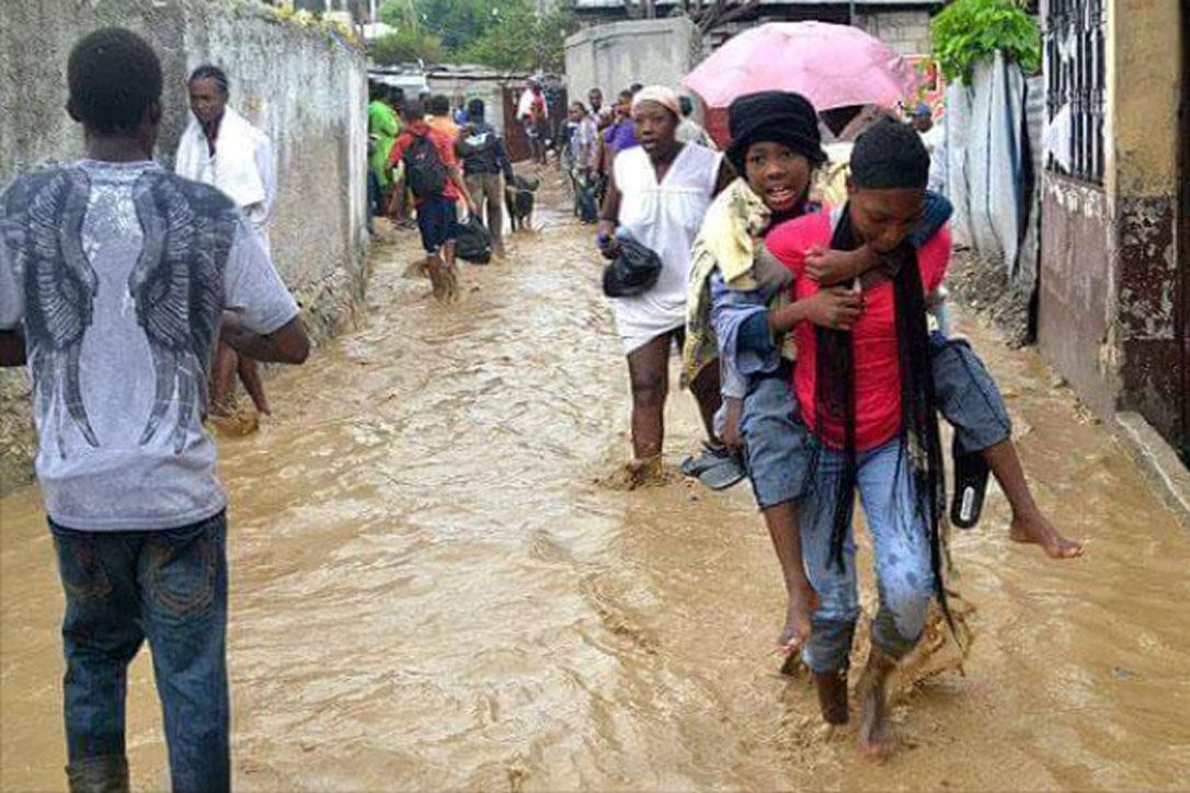 A survivor is carried to safety through a flooded street. Photos: LWF Haiti 