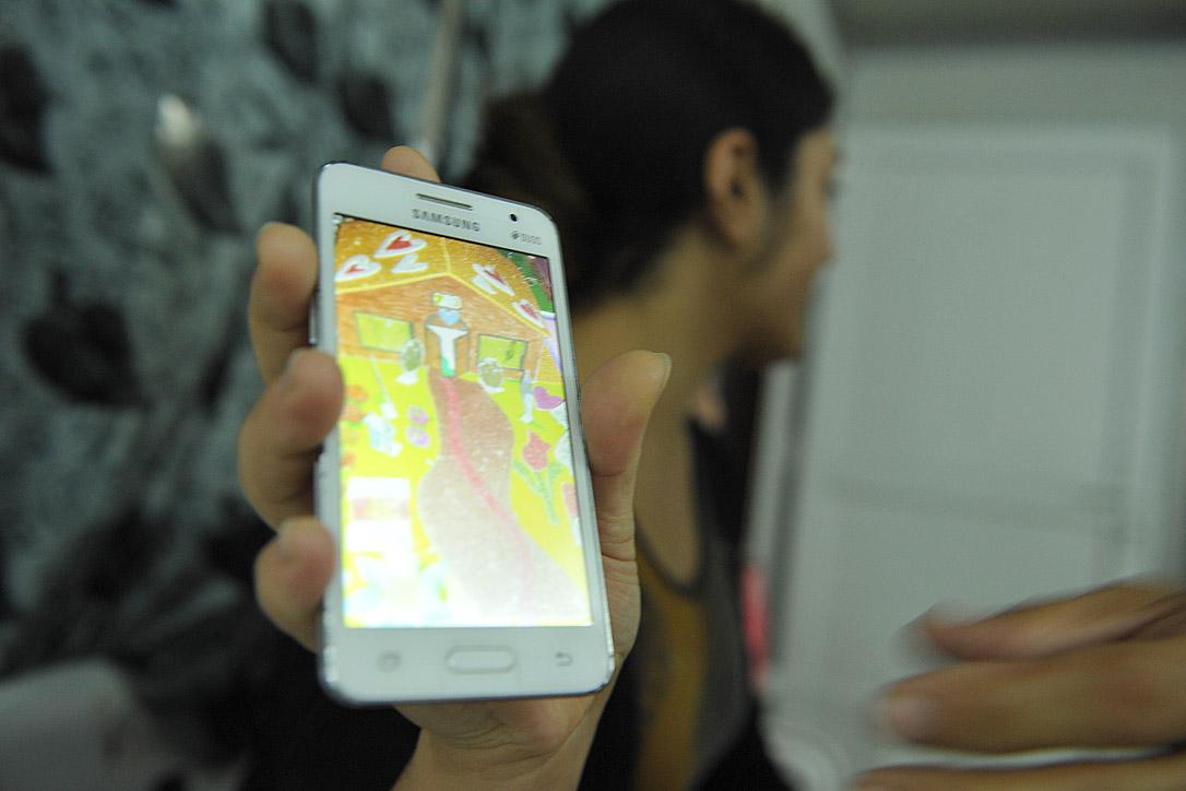 Ein Haus mit vielen Farben und Herzen: Asna (Name geändert) zeigt auf ihrem Handy ein Bild, das sie während eines ihrer Kunstworkshops gemalt hat. Foto: LWB/C. Kästner