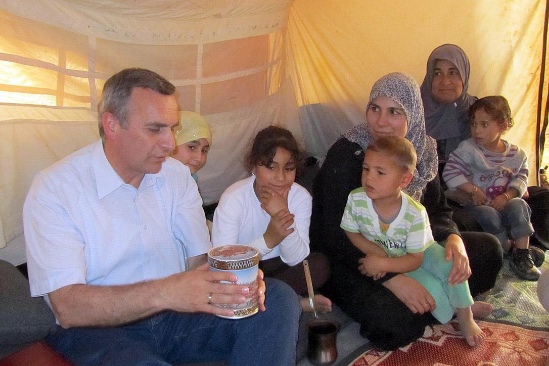 Pfr. Michael Martin schenkt einer syrischen Familie im Flüchtlingslager Za‘atari eine Dose mit Süssigkeiten. Foto: LWB Jordanien/E. Gano