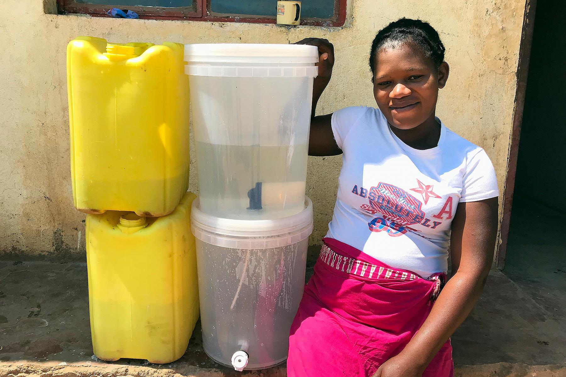 Zikhai Suela aus dem Dorf Mpengo zeigt vom LWB verteilte Wasserfilter und Gallonen. Foto: LWB/B. Khanal