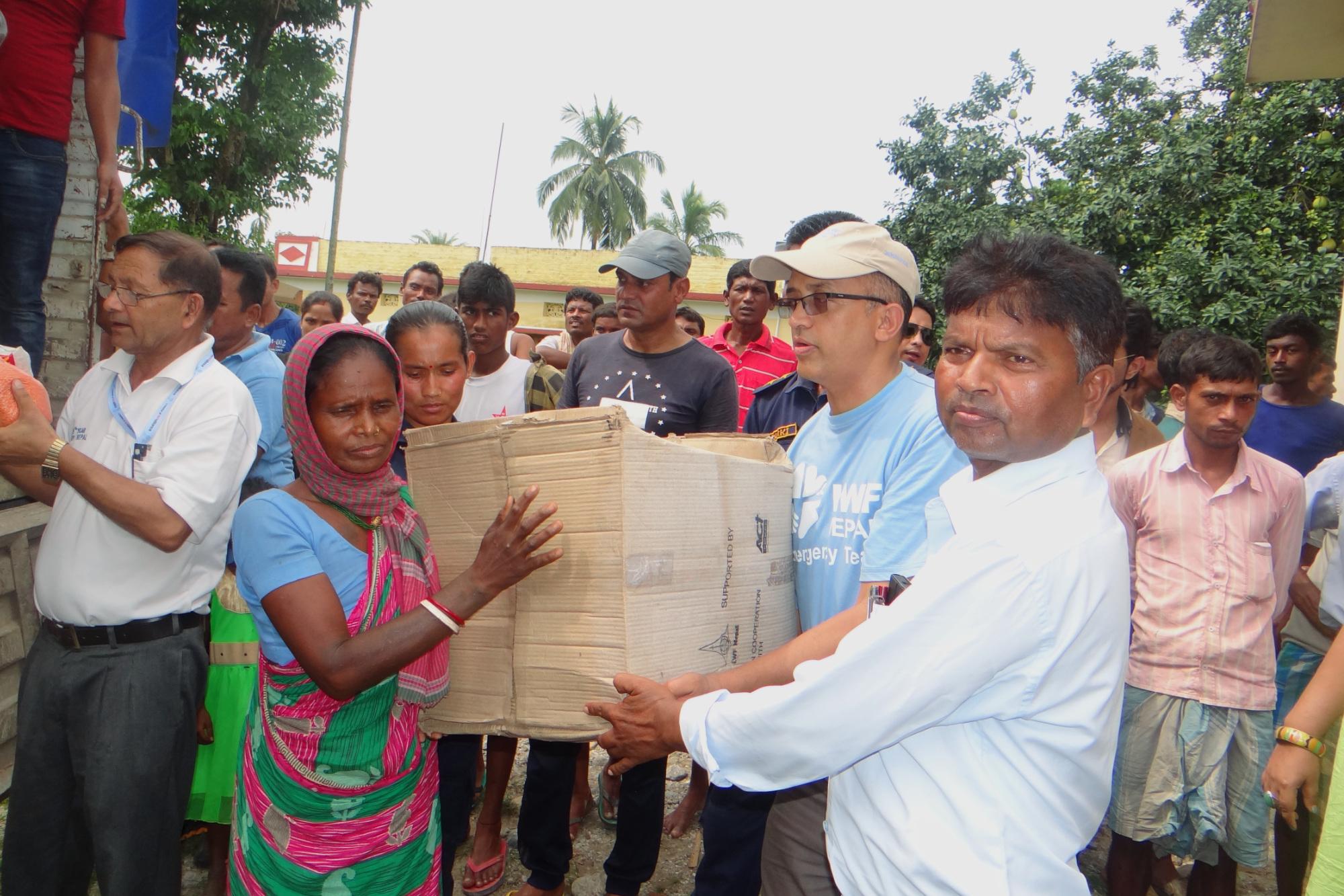 A member of a flood affected family in Jhapa Rural Municipality receives a box containing food, blankets and kitchen utensils provided by LWF Nepal and its partner organization in Jhapa. Photo: LWF/ Prabesh Bhandari 