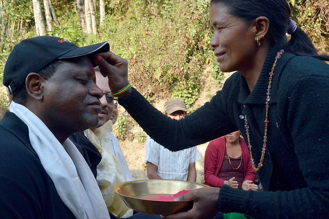 ACT-Generalsekretär John Nduna empfängt von einer Frau aus Sanogoan das Tika, ein traditionelles Stirnmal. Foto: LWB/ Lucia de Vries