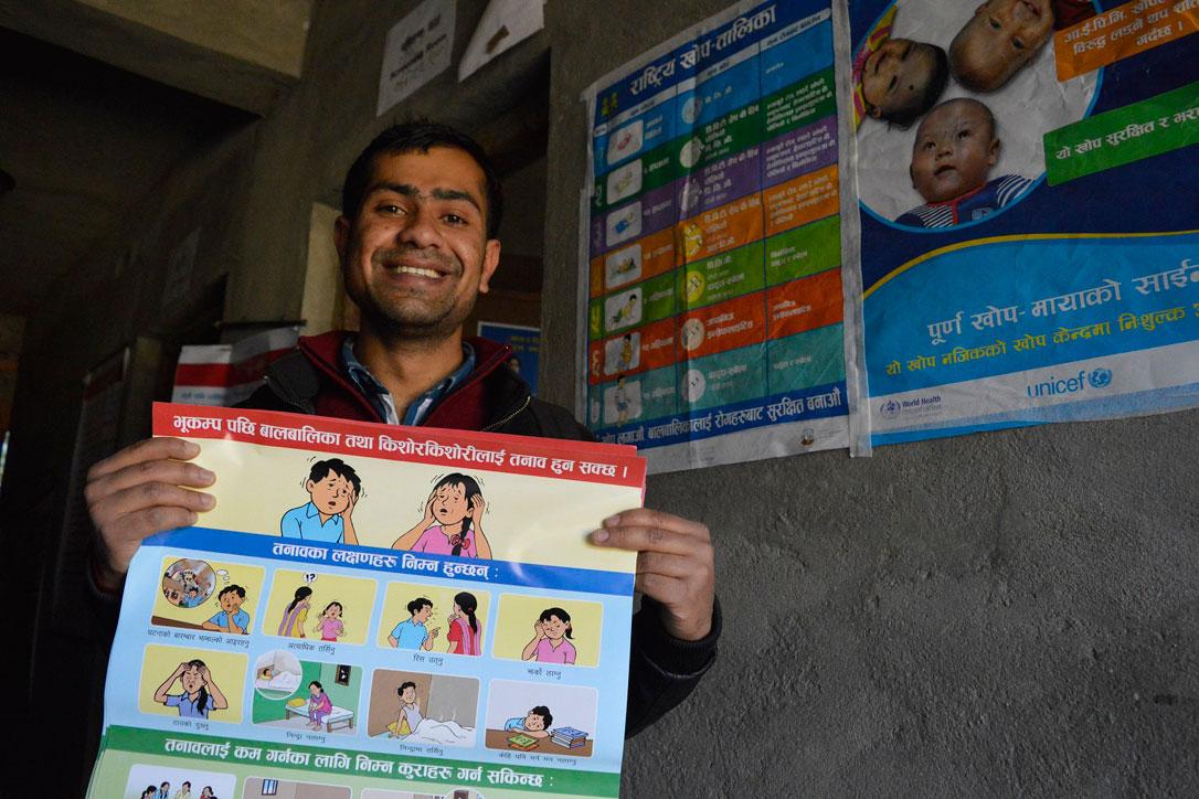Posters, like the one held by counselor Pradeep Subedi, show the psychological impact of earthquakes on children. Photo: LWF/Lucia de Vries
