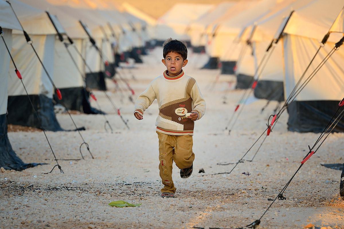 Ein Junge aus dem Zaatari Flüchtlingslager in der Nähe von Mafraq (Jordanien), läuft morgens zwischen den Zeltreihen entlang. Das Lager wurde 2012 eröffnet und beherbergt 20.000 syrische Flüchtlinge. Ihre Zahl steigt weiter an. Foto: Paul Jeffrey/ACT