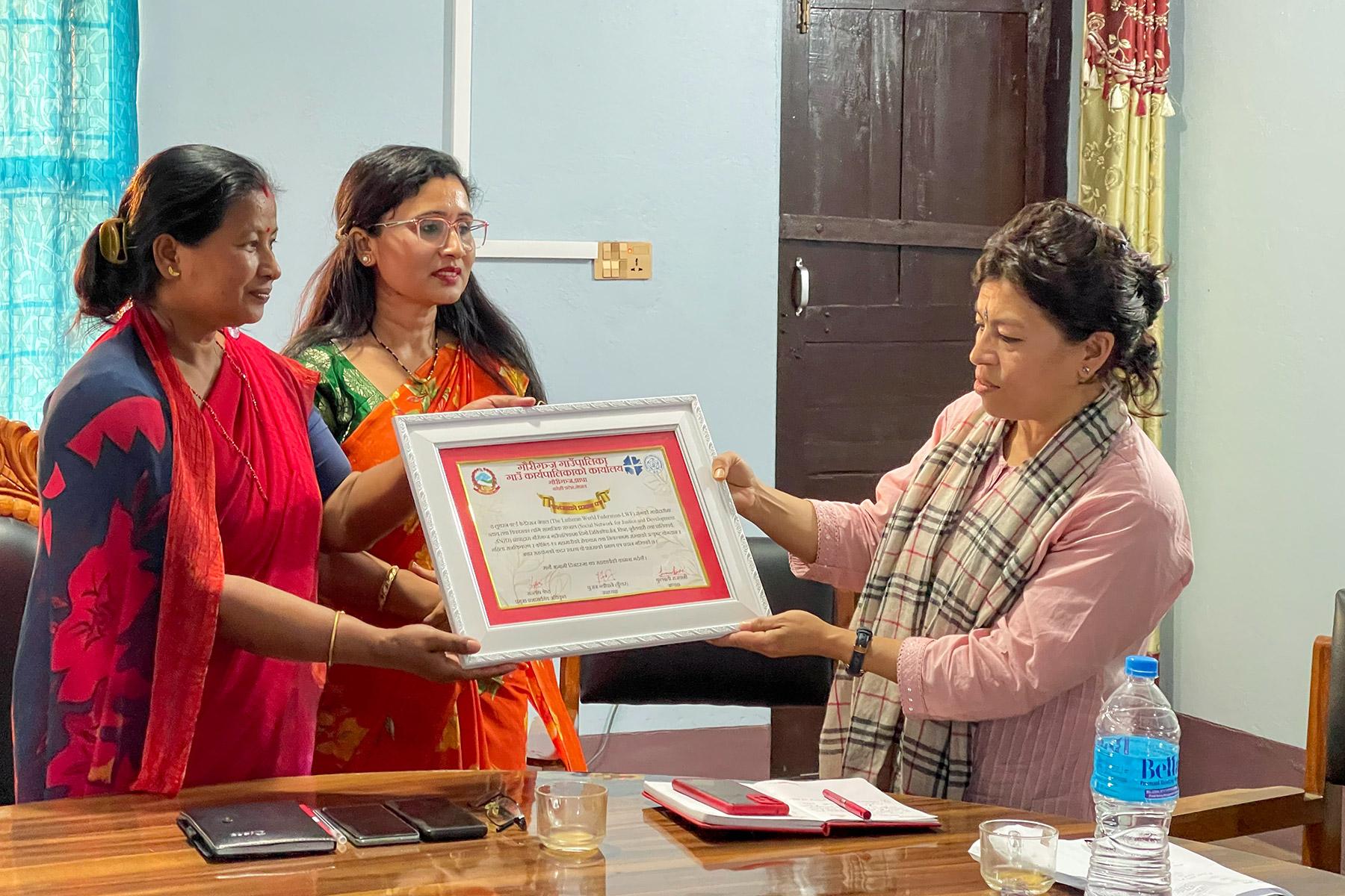 El representante de la FLM en Nepal, Dr. Bijaya Bajracharya (derecha), recibe una carta de agradecimiento de los líderes del gobierno local. La carta fue emitida por el gobierno local y agradece la colaboración con la FLM y su organización local asociada SNJD en el distrito de Jhapa. Foto: FLM/ Y. Gautam