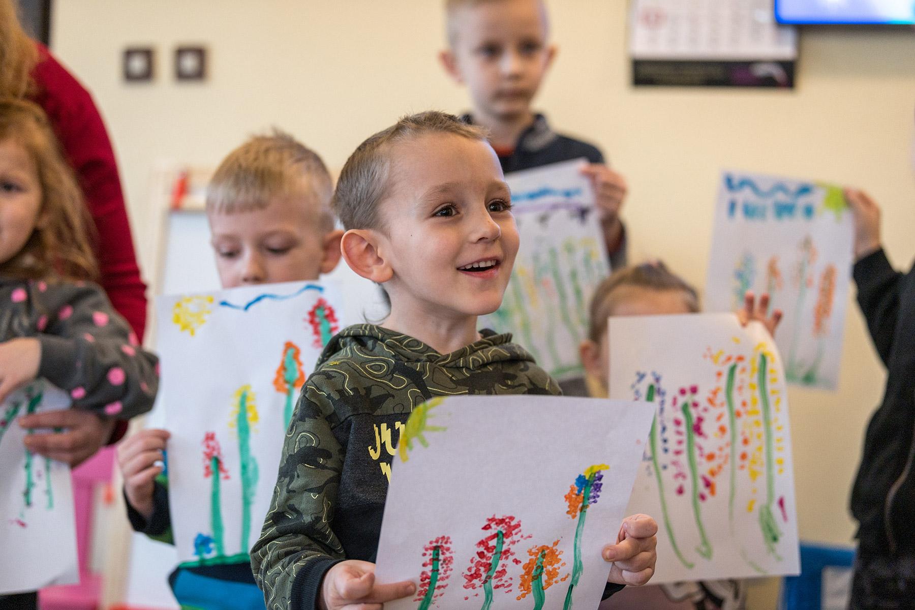 Ein Junge zeigt ein Bild, das er bei der Kinderbetreuung im LWB-Gemeindezentrum gemalt hat