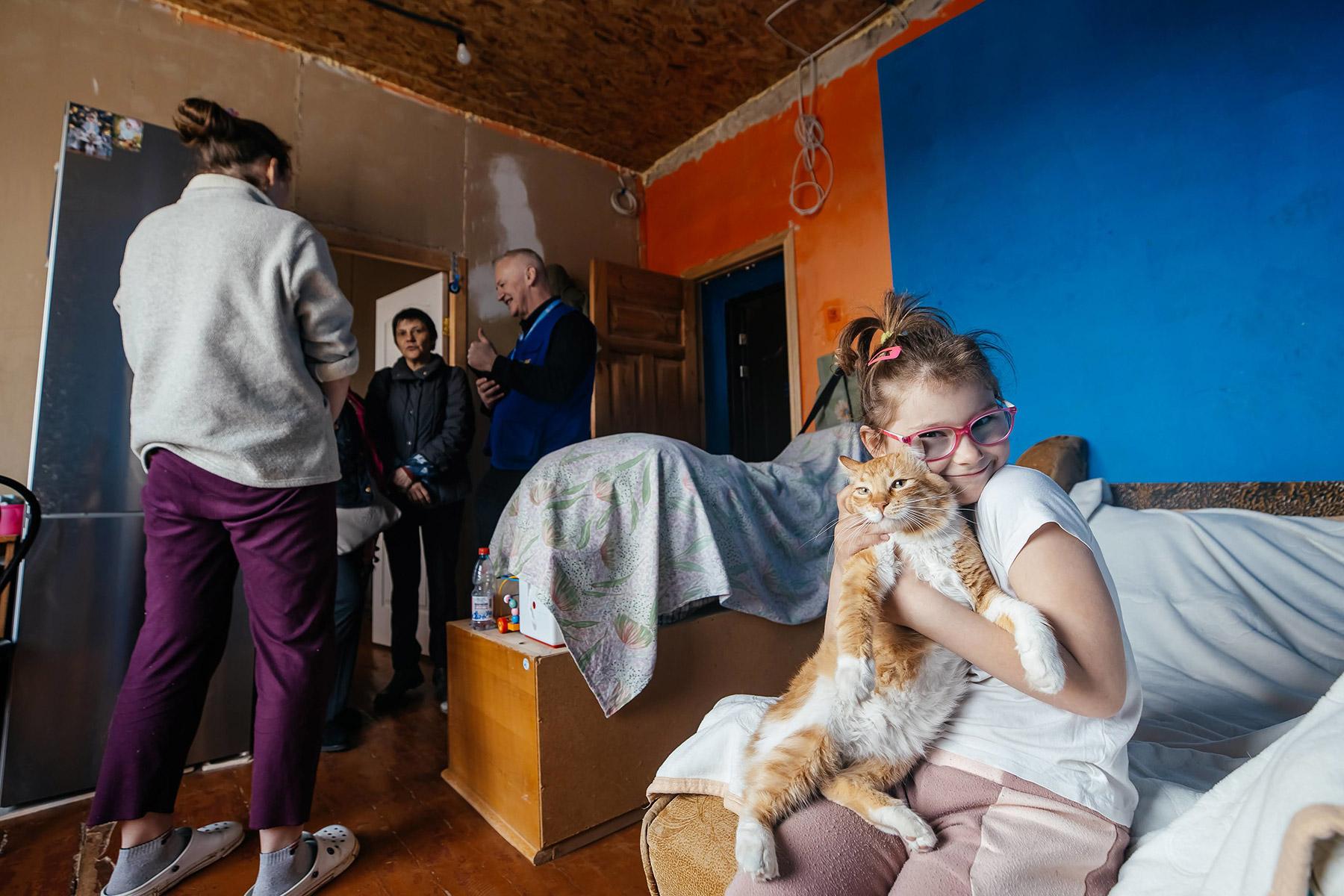 Una niña sostiene a su gato mientras un equipo de la FLM discute las necesidades de reconstrucción con su madre. Foto: FLM/ Anantoliy Nazarenko