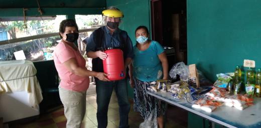 Hans-JÃ¼rgen Johnke (middle), Mission EineWelt staff working in El Salvador, hands over food and a canister for washing hands to members of the congregation in El Volcan. Photo: MEW 