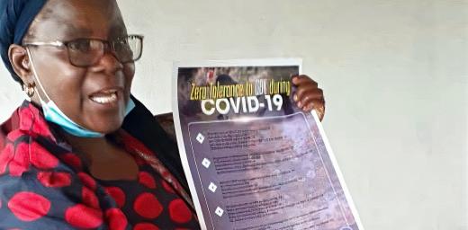 The Rev. Elitha Moyo displays a COVID-19 best practices and gender-based violence prevention poster in the Mberengwa Ward 23 area, a border community in Zimbabwe at increased risk for both. Photo: ELCZ
