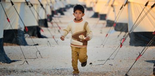 Early in the morning, a boy runs amid the tents in the Zaatari Refugee Camp, located near Mafraq, Jordan. Opened in July, 2012, the camp holds upwards of 20,000 refugees from the civil war inside Syria, but its numbers are growing. Photo: Paul Jeffrey/ACT