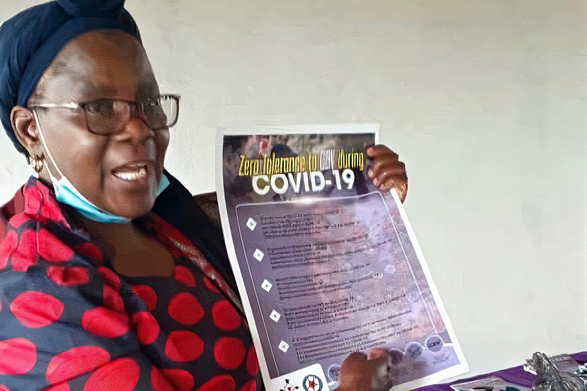 The Rev. Elitha Moyo displays a COVID-19 best practices and gender-based violence prevention poster in the Mberengwa Ward 23 area, a border community in Zimbabwe at increased risk for both. Photo: ELCZ