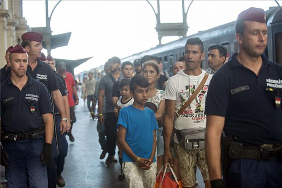 Refugees in Hungary are escorted along a train platform. Photo: MTI