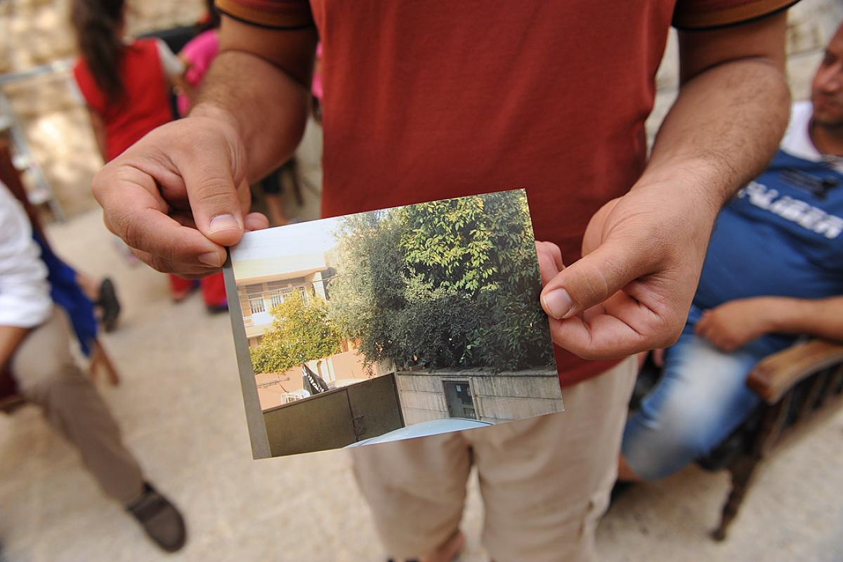 A refugee shows a photo of his house. It has been confiscated and marked as IS property. Photo: LWF/M. Rénaux