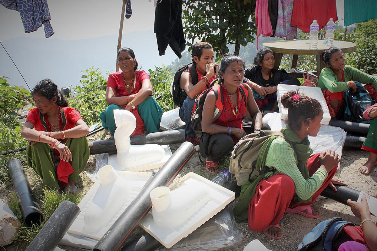 Sita, middle, and neighbours sitting among emergency toilet kits. Photo: Lucia de Vries