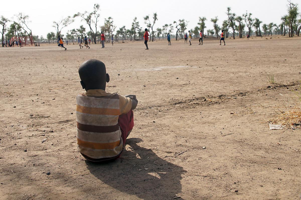 A little boy watches a football game in a child friendly space, Gendrassa refugee camp, South Sudan. Photo: LWF/ C. Kästner