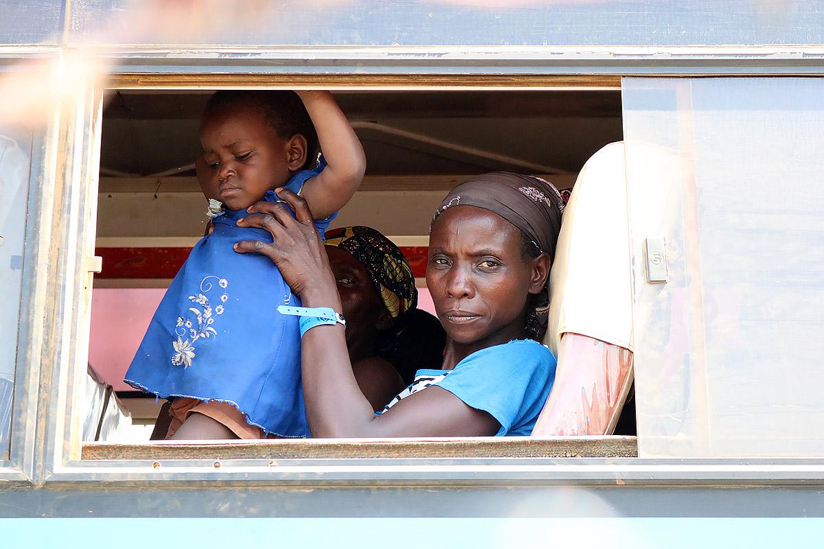 A woman newly arrived from the DRC holds a child as they wait to be moved from the Sebagoro landing site. LWF Uganda is at the frontline of the refugee response. All Photos:  LWF Uganda / S. Nalubega