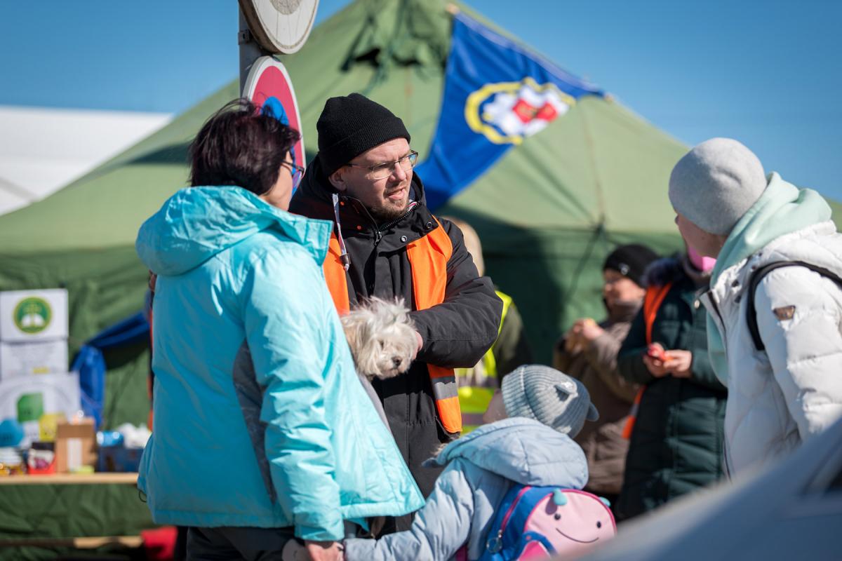 March 2022: A volunteer at a church-run support point at the Vyšné Nemecké border crossing between Slovakia and Ukraine shares information with a refugee family who have just arrived in Slovakia. At the onset of the war, the border crossing at Vyšné Nemecké saw up to some 10,000 refugees cross each day. Photo: LWF/Albin Hillert